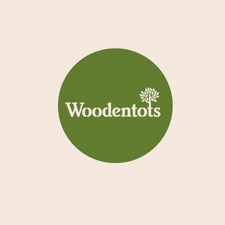 Woodentots Montessori School logo. A forest green circle, filled in, with the word Woodentots in the center in tan. The final t in woodentots is shaped like a tree. 